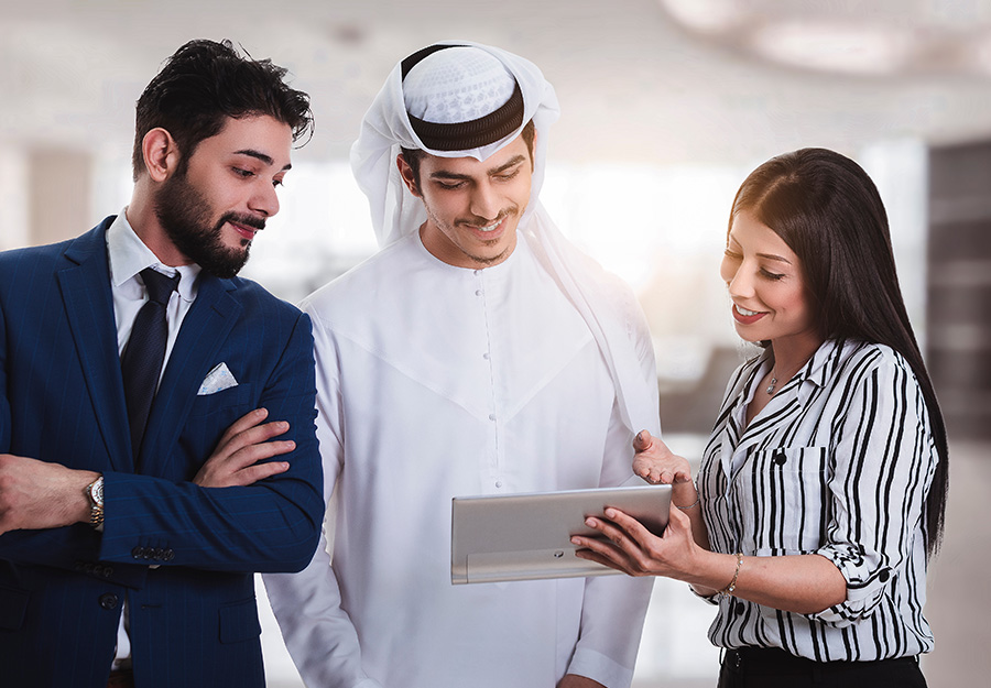 Three professionals are having a work discussion while viewing information on a tablet.